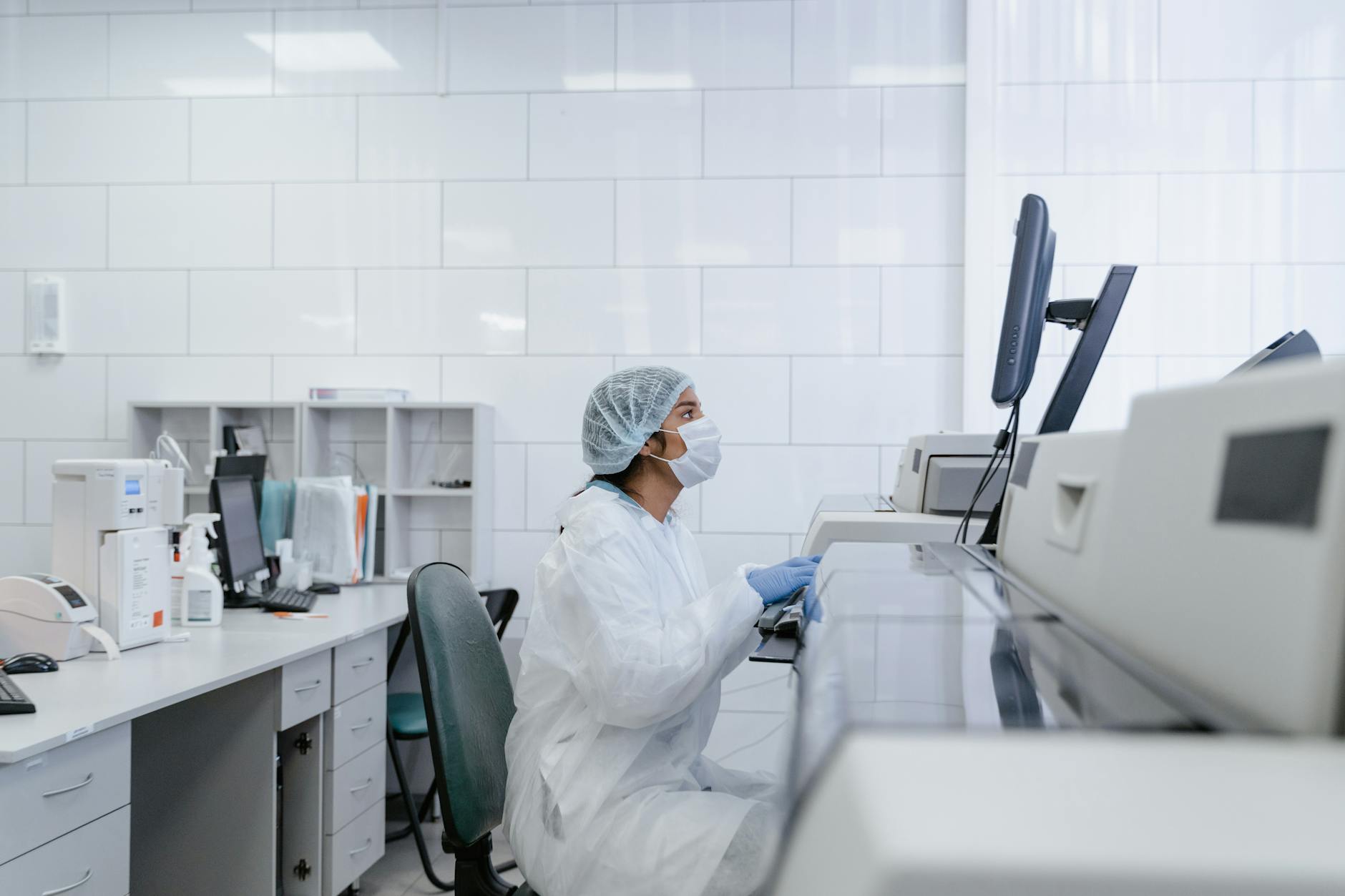 healthcare professional in PPR kit checking computer in laboratory