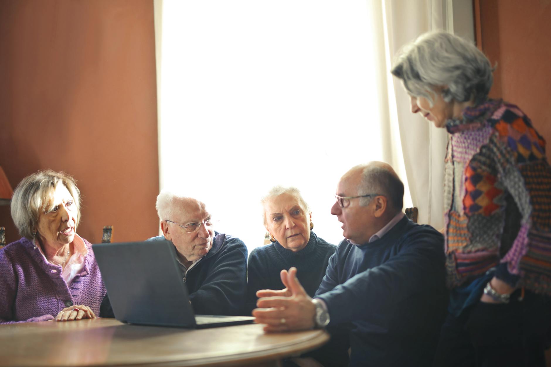 elderly people sitting at table with laptop