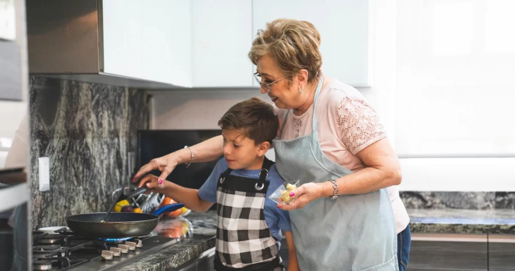 US senior cooking food with her grandson.