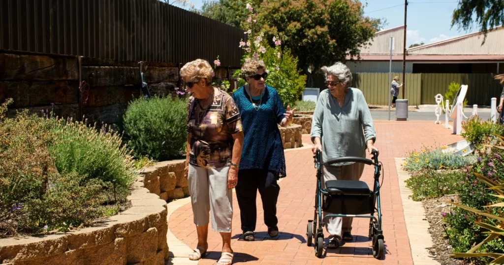 Three senior ladies in the US set out on a walk in a park.